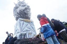 Aremania tabur bunga di depan patung singa di Stadion Kanjuruhan Malang